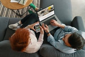 male and female couple searching real estate on laptop and phone