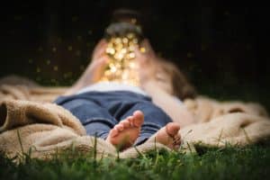 girl laying down with jar of fireflies